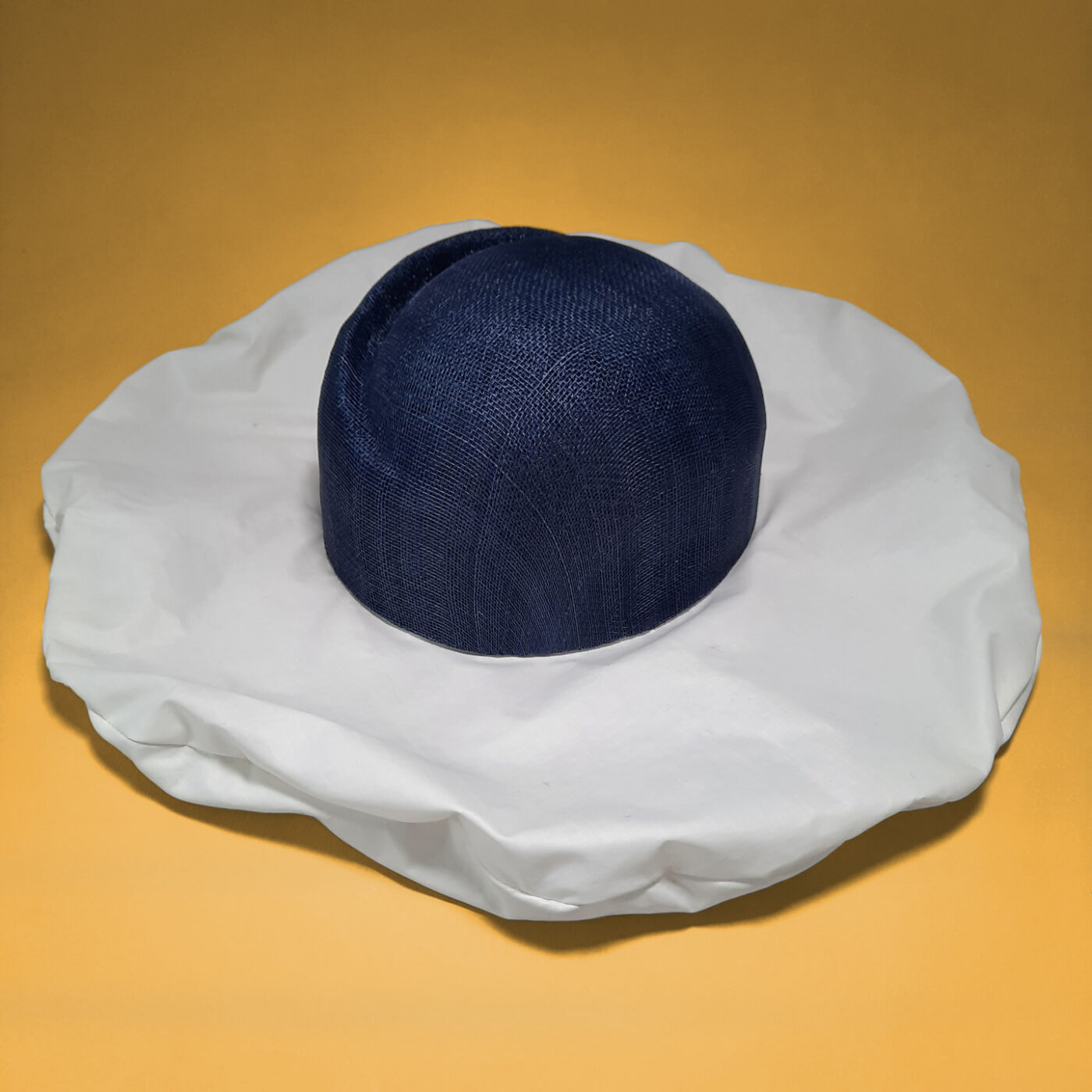 A designer summer hat with an original brim made of upcycled white sail which contrasts with the navy blue straw crown.
