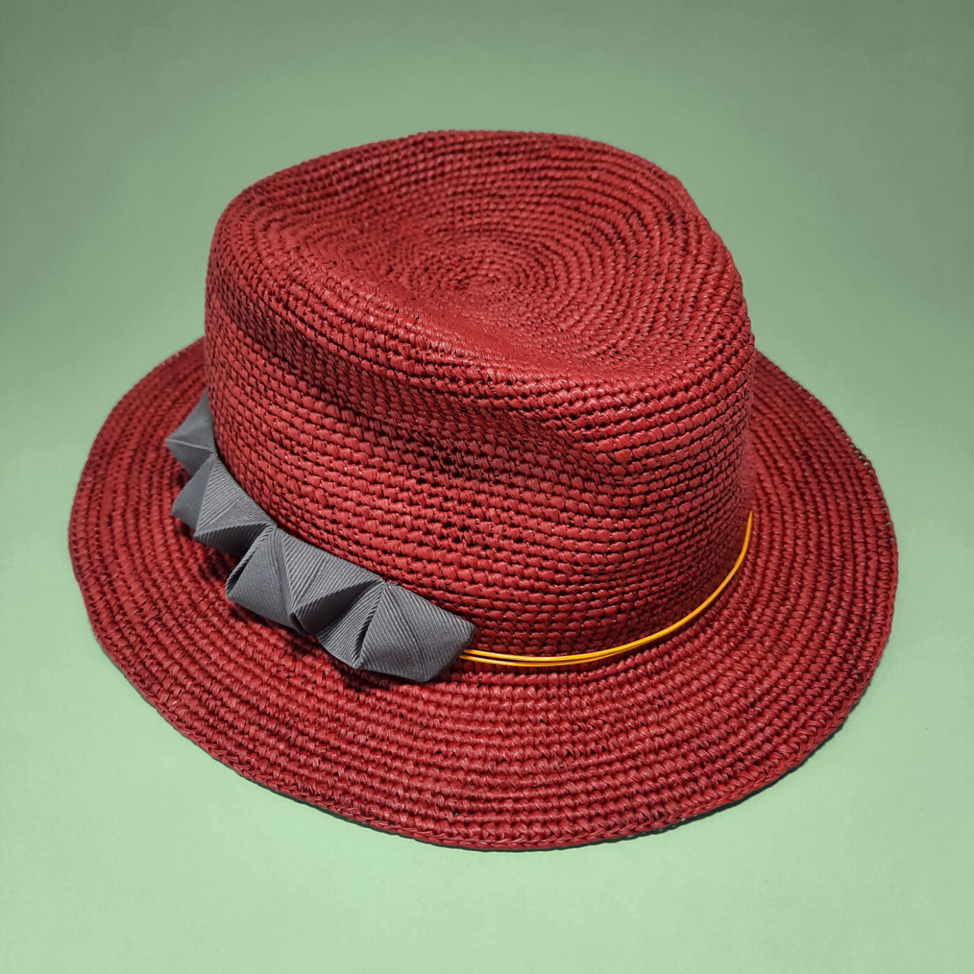 A red summer fedora made of crocheted panama straw. It's a unique hat that you can customize with a chameleon detail.