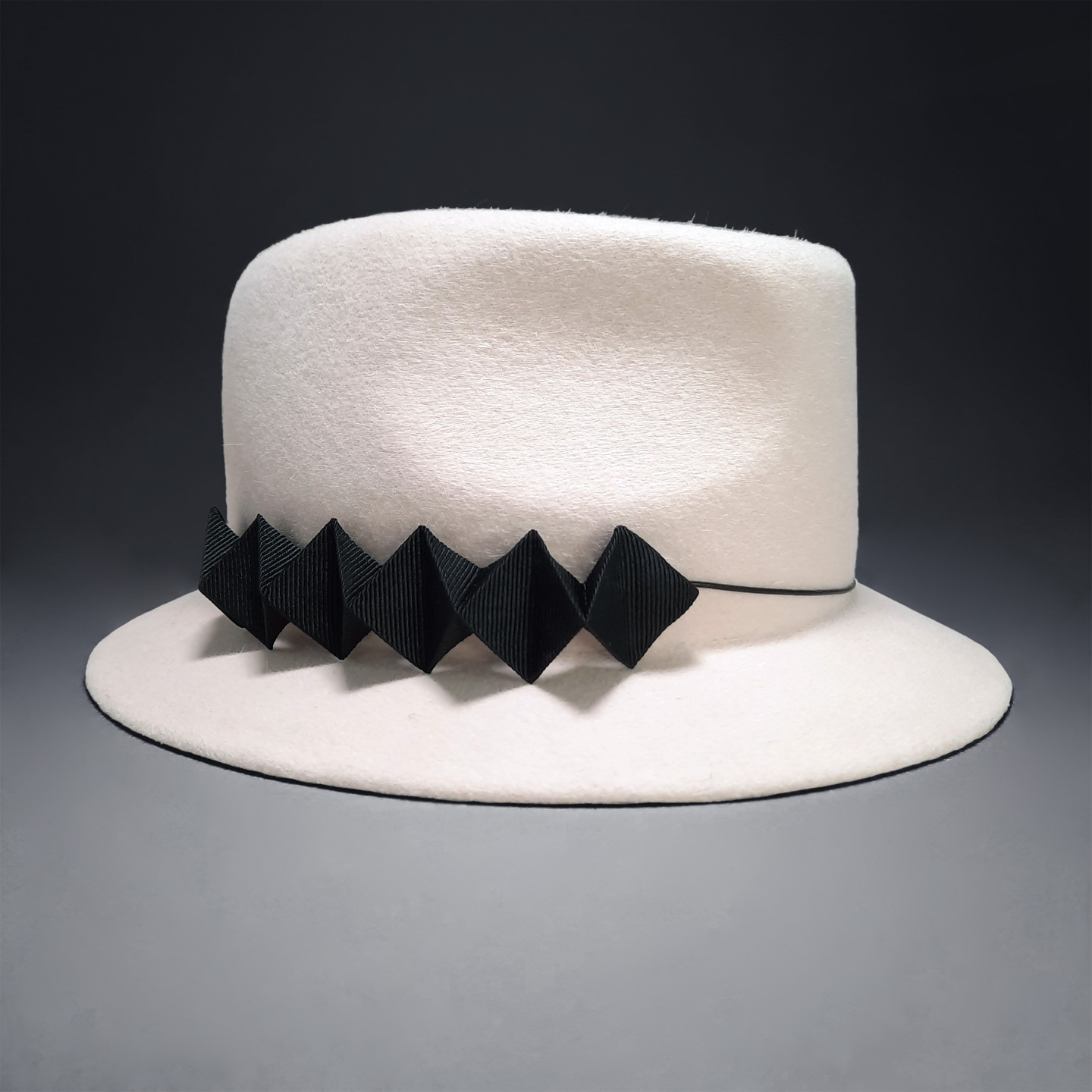 A white fedora with a black 3d chameleon detail, a designer hat that is a true fashion statement. Hand made in France.
