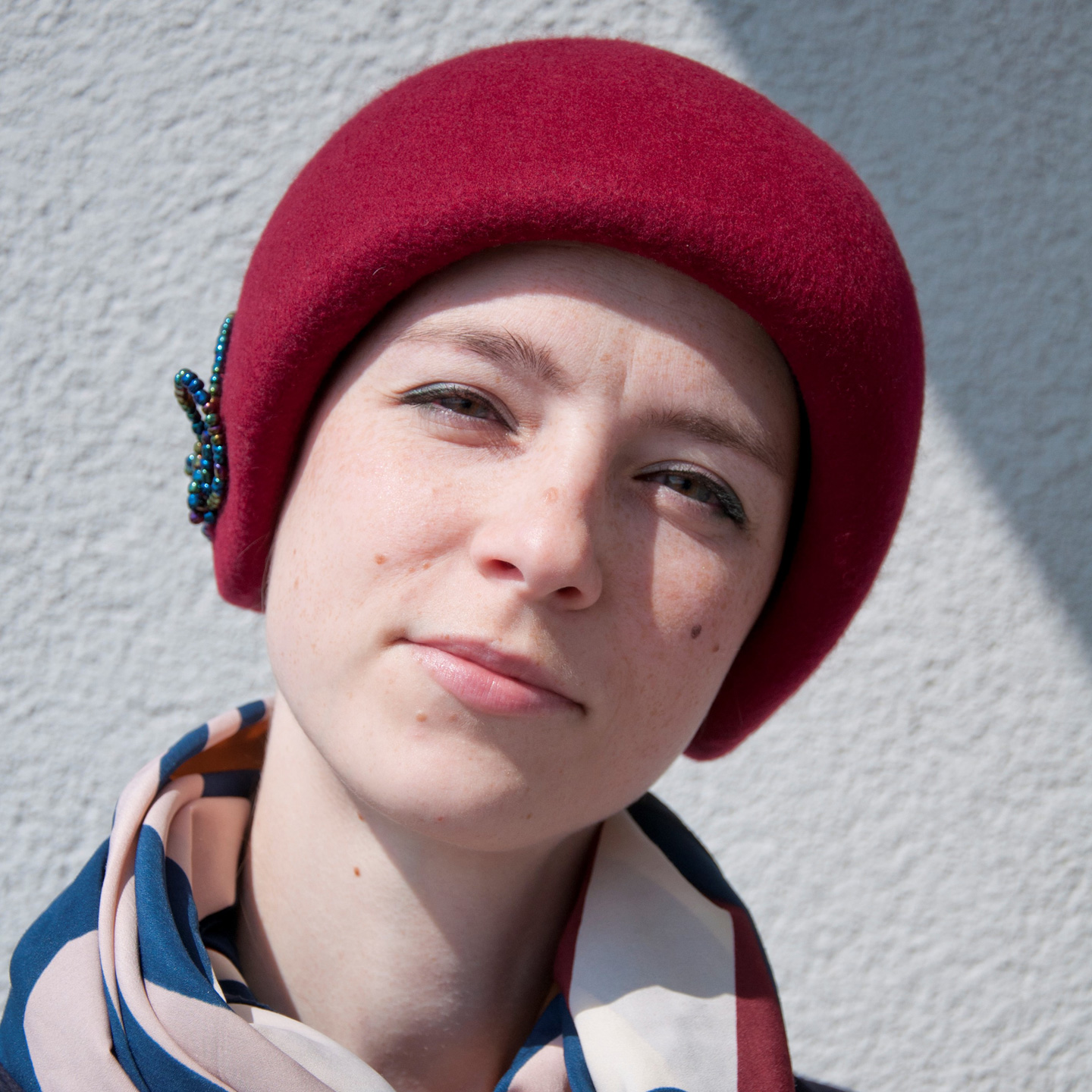 A young woman in a custom-made 1920s inspired hat. This helmet-like headpiece was made to measure form a red fur felt.