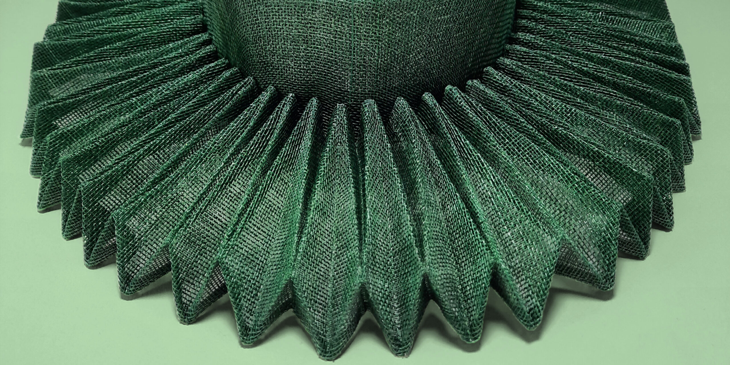 A summer hat by a new wearable art designer. It's a head jewel made from emerald green sinamay with a stunning origami brim.