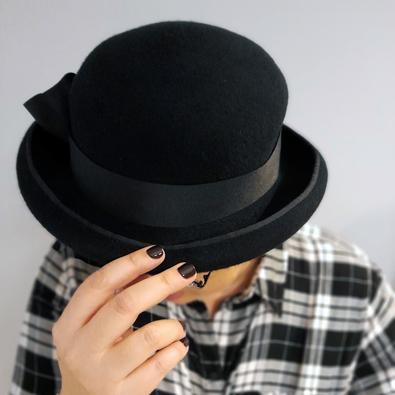 An owner of a black melusine bowler with classic finishing touches like satin petersham ribbon around the crown and the brim.