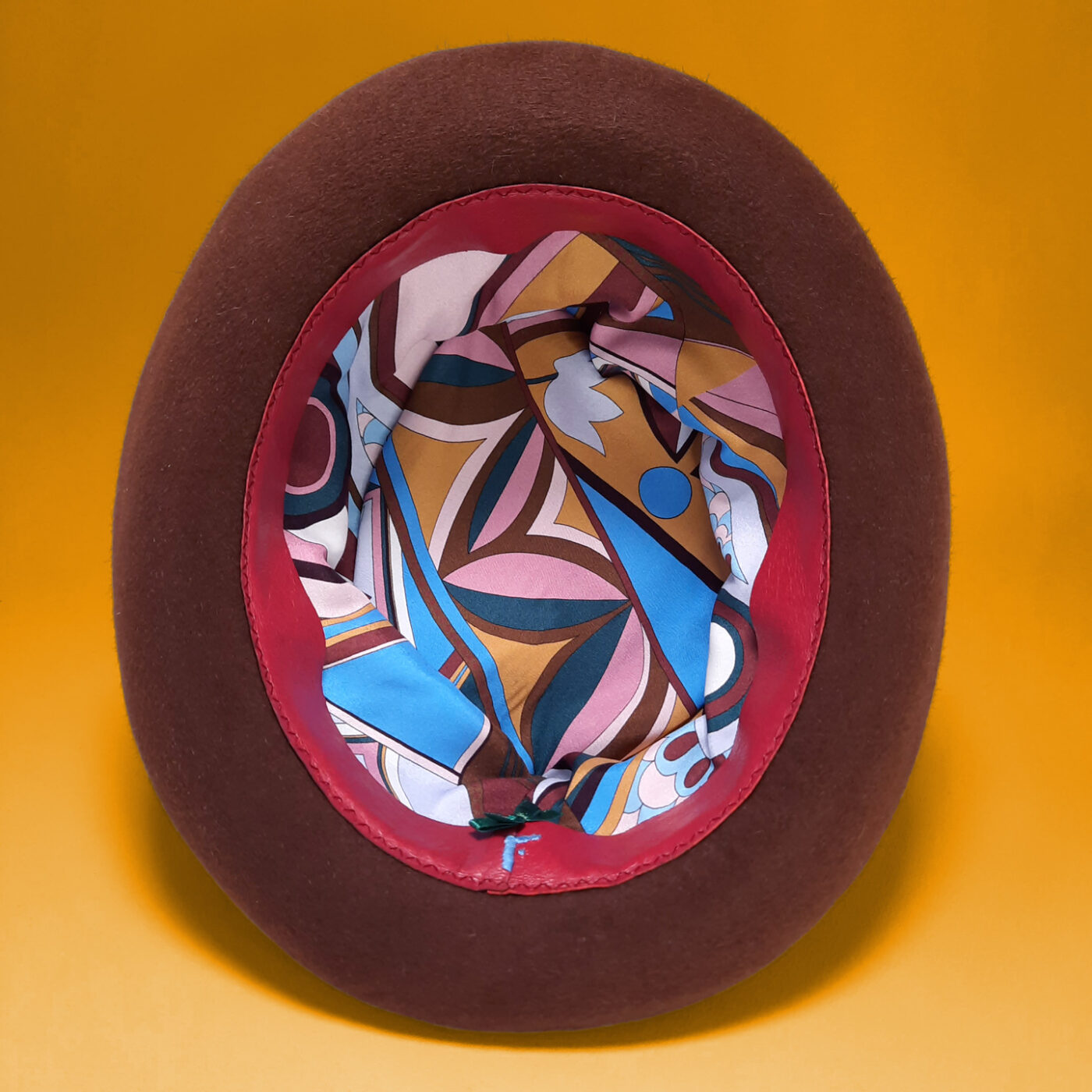 The inside of a luxury hat: a silk lining and a leather sweatband signed with an embroidered F which identifies Fusanna hats.